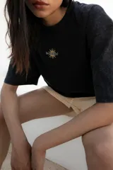 Remera negra de corte oversize con estampa trasera con un sol y texto en color naranja.