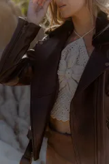 Campera de cuero marrón chocolate con acabado vintage, cuello solapa con piel de corderito desmontable, avíos metálicos en bronce viejo, cinto con hebilla para ajustar la cintura, cierres funcionales en puños y bolsillos laterales e interior forrado.