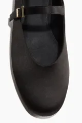 Ballerinas negras de satén, estilo guillerminas, con punta almendrada, tira sobre el empeine con hebilla dorada y taco bajo.