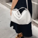 Bolso bandolera blanco de cuero con correa ajustable y cierre superior.