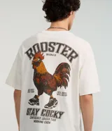 Remera color crudo de corte boxy, con cuello redondo y mangas cortas. Estampado trasero con un gallo con gafas y zapatillas, la palabra 'Rooster' y la frase 'Stay Cocky'.