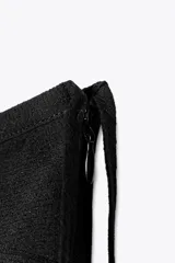 Falda pantalón corta negra con volantes y lazo lateral con abalorios. Cierre lateral con cremallera oculta y forro interior.