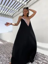 Vestido largo negro con escote en V y apliques de lentejuelas doradas en el corpiño.