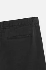 Bermuda negra regular fit confeccionada en tejido con mezcla de algodón y lino. Cintura elástica ajustable con cordón. Pliegues frontales. Bolsillos laterales y traseros de vivo. Cierre frontal con cremallera y botón.