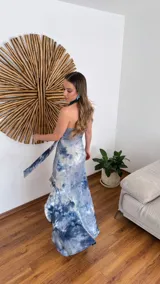 Vestido largo de fiesta con estampado tie-dye en tonos de azul y blanco. Presenta escote halter con lazos y abertura lateral en la falda.