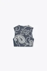 Chaleco de denim azul con bordado floral blanco, escote en V, cierre frontal con botones y bolsillos laterales.