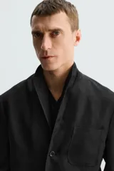 Blazer relaxed fit de lino color negro, con cuello solapa, manga larga, bolsillos frontales de plastrón y cierre frontal con botones. Interior sin forro.