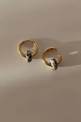 Par de aros dorados tipo argolla con dije cilíndrico de piedra natural color crema con manchas negras.