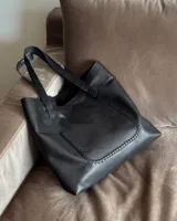 Bolso tote negro de cuero vacuno con costuras a la vista.