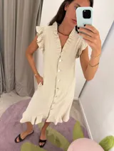 Vestido midi color beige, con escote en V, abotonado al frente y mangas cortas con volados. Confeccionado en lino y algodón.