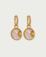 Par de aros dorados de acero quirúrgico hipoalergénico con baño en oro 18K y dije circular con incrustación de nácar y diseño de rayos de sol.