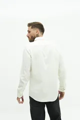 Camisa blanca de manga larga texturizada, tejida en dobby, con cuello italiano y cartera abotonada. Tiene un logo bordado en el pecho.
