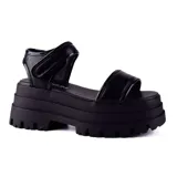 Sandalias negras con plataforma alta y suela track. Tiras anchas sobre el empeine y ajuste con velcro en el tobillo.