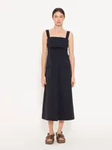 Vestido midi negro de poplin con lycra, silueta línea A, bolsillos laterales y tajo en el centro delantero. Se ajusta en la espalda con un lazo.