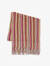 Poncho de punto multicolor con diseño de ondas en zigzag y flecos en el borde inferior.