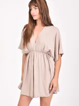 Monoprenda corta color beige claro con escote en V profundo, mangas cortas tipo mariposa y cintura fruncida elástica.