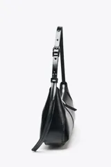 Bolso de hombro negro de cuero sintético, con asa ajustable con hebilla metálica, bolsillo interior con cremallera y cierre principal con cremallera.