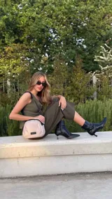 Bandolera pequeña de tela negra, con correa ancha ajustable y cierre superior.