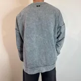Buzo celeste con efecto gastado, corte oversize, cuello redondo y puños y ruedo acanalados.