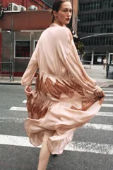 Vestido midi color beige con detalles de encaje marrón, cuello alto con lazo, escote pico, manga larga y botones frontales.