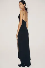 Vestido largo negro de tejido crepe, con escote en V pronunciado y tirantes finos ajustables. Presenta aberturas laterales en el bajo.