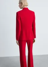 Traje sastrero rojo compuesto por blazer de corte recto con solapas de muesca y cierre de doble botón, chaleco con escote en V y pantalón de vestir de corte recto.