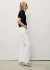 Pantalón de jean blanco, de corte recto, con tiro medio, cinco bolsillos y cierre frontal con cremallera y botón.