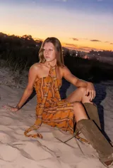 Vestido midi strapless color dorado con estampado de hojas y rayas verticales. Incluye una tira de tela que se ata al cuello.