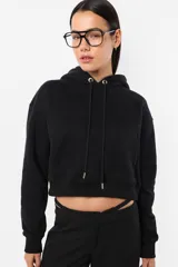 Buzo negro corto con capucha y bolsillo canguro. Tiene cordón ajustable con punteras metálicas y puños y cintura en rib.