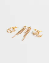 Set de tres pares de aros dorados: argollas clásicas, argollas dobles con strass y aros colgantes con strass.