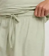 Conjunto de pijama corto para hombre, compuesto por una remera de manga corta con cuello redondo y un short con cintura elástica y cordón de ajuste. El tejido es malla flameada con efecto mezcla en tono verde claro.