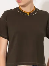 Remera verde militar de punto pesado con tachas aplicadas a mano en el escote y los hombros.