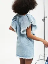 Vestido corto de jean celeste con volados en los hombros y ruedo desflecado.
