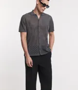 Camisa de punto gris con cuello inglés, mangas cortas, abotonadura frontal y textura geométrica.