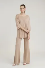 Conjunto de sweater y pantalón color beige con brillo metalizado. El sweater es holgado, de mangas 3/4 y cuello redondo. El pantalón es de corte palazzo.
