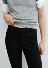 Pantalón negro de diseño crop, corte skinny y tiro medio. Cuenta con trabillas, dos bolsillos laterales, dos bolsillos de ribete en la parte posterior, cierre de cremallera y botón, y forro interior.