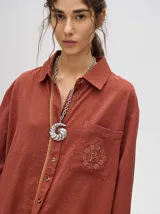 Camisa celeste de corte holgado con bolsillo en el pecho con logo bordado. Detalle de diseño en cartera de botones y puños con ribete a contraste.