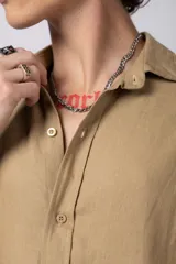 Camisa color arena de lino, manga larga, con cuello clásico y corte holgado.