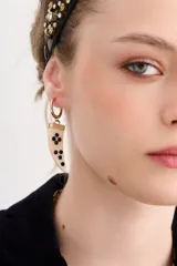 Aros colgantes dorados con forma de argolla pequeña y dije en forma de cuerno de resina con incrustaciones de strass.