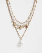 Set de tres collares cortos dorados. Uno con eslabones, otro con perlas y el tercero con dije de corazón alado y perla colgante.