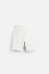Bermuda color beige de corte recto, con cintura elástica ajustable con cordón, detalle de pliegues frontales, bolsillos laterales y bolsillos de vivo en la espalda.