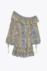 Vestido corto con estampado paisley en tonos ocre, azul y marrón. Tiene escote recto con volantes, mangas largas abullonadas con puños elásticos y cintura elástica.