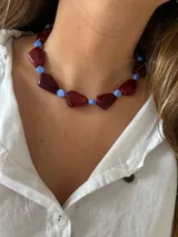 Collar corto con cuentas irregulares de resina color bordó veteado, intercaladas con cuentas redondas pequeñas de color celeste.