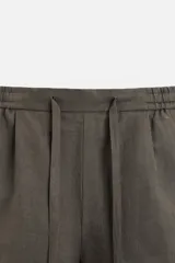 Bermuda regular fit negra confeccionada en tejido de lino. Cintura elástica ajustable con cordón y pliegues frontales. Bolsillos frontales y detalle de bolsillos traseros de plastrón.
