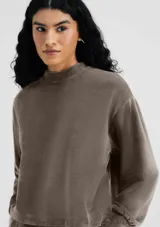 Buzo color beige en tela acanalada con cuello alto y puños ajustados.