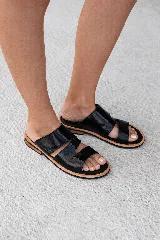 Sandalia tipo slide de cuero color marrón oscuro, con dos tiras ajustables sobre el empeine. La tira superior es de gamuza y la inferior tiene textura de cocodrilo. La plantilla es acolchada y forrada en cuero.