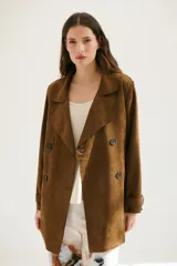 Trench simil gamuza color marrón, con cuello de solapa muesca, cuatro botones delanteros, bolsillos laterales y cinturón a la altura de la cintura.