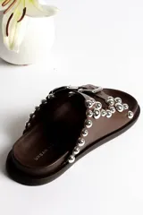 Sandalias marrones de cuero con dos tiras con hebillas ajustables y detalle de tachas plateadas.