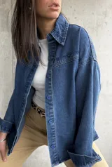 Sobrecamisa de denim azul con bordados florales en cuello y hombros, cierre frontal con botones azules y corte holgado.