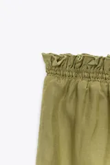 Falda midi color verde oliva confeccionada en tejido con viscosa. Presenta cintura elástica y detalle de volantes en el mismo tejido.
